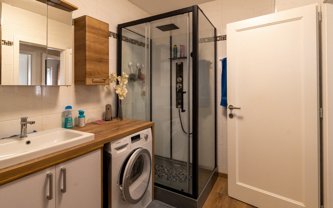 Modernes Badezimmer mit begehbarer Duschkabine und praktischer Wäscheintegration
