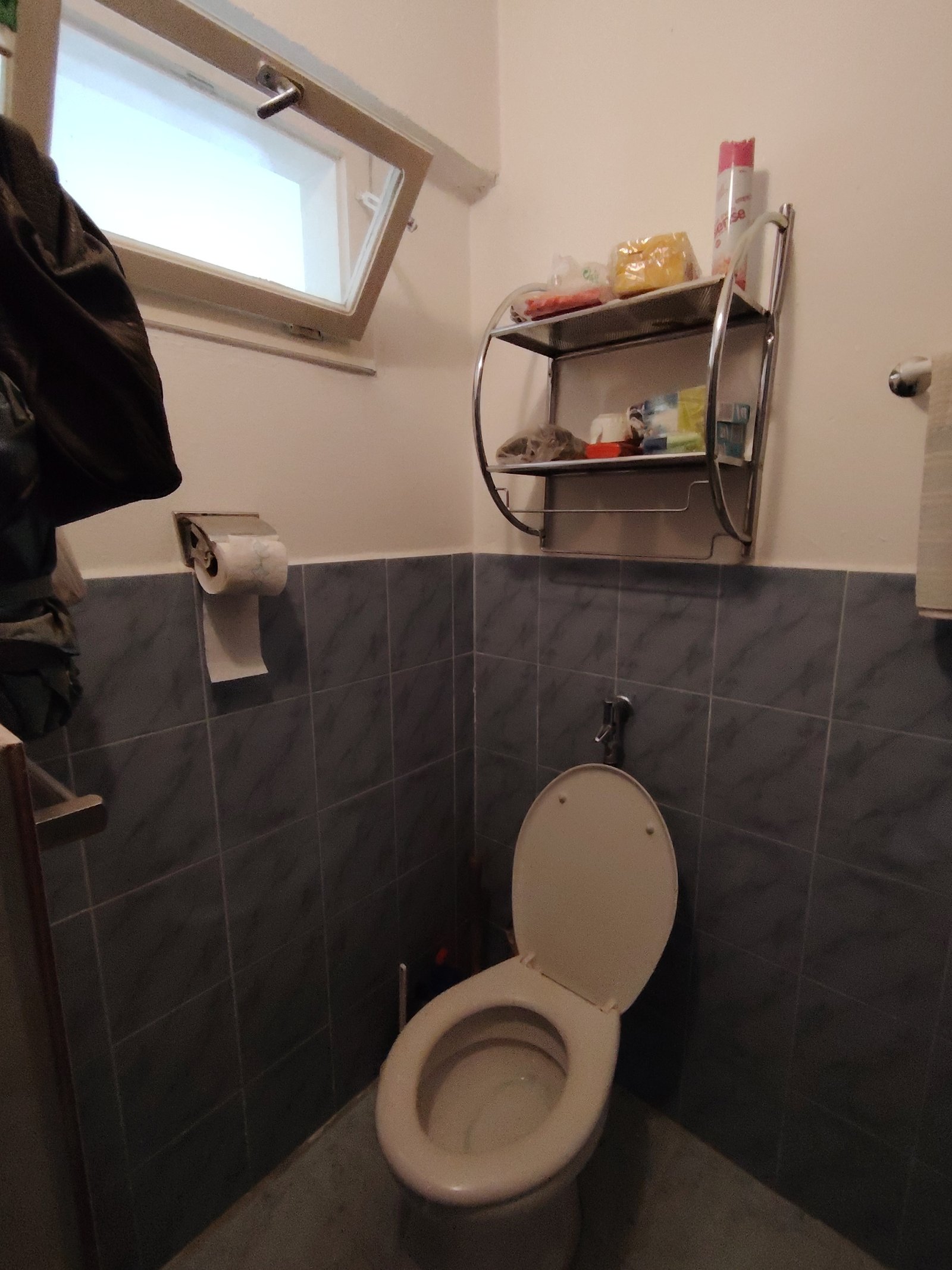 Bright guest bathroom with a practical wall shelf and elegant tiled mirror