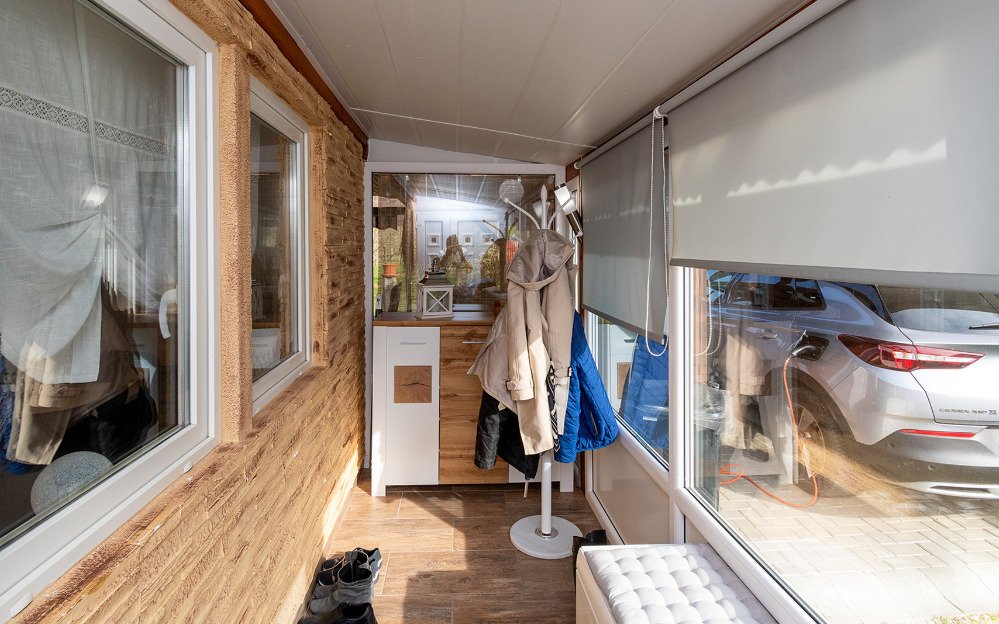 Zonnige loggia met grote glaspartijen en hoogwaardige houten afwerking